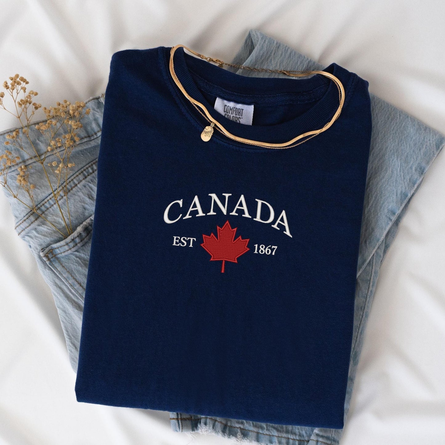 a canada t - shirt sitting on top of a pair of jeans