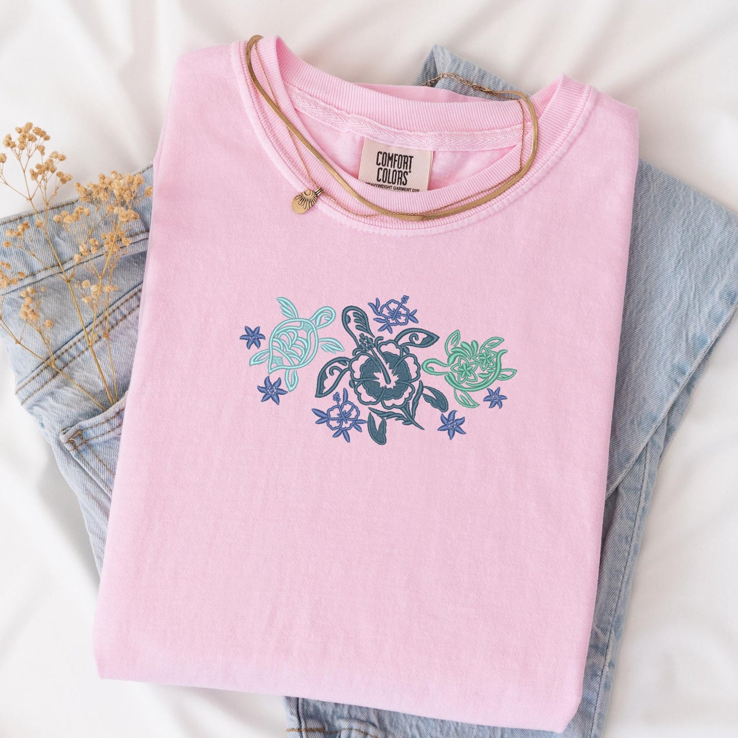 a pink shirt with a turtle on it next to a pair of jeans