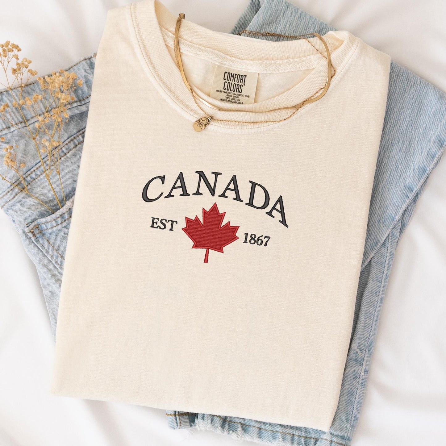 a canada t - shirt is laying on a bed next to a pair of jeans