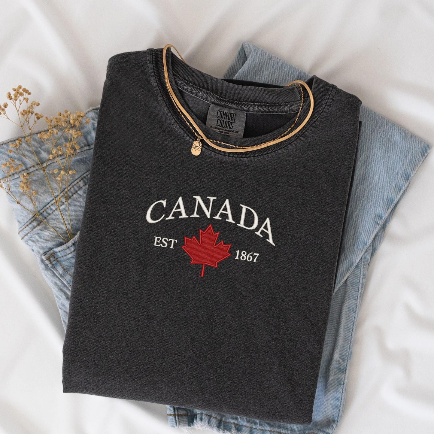a canada t - shirt sitting on top of a pair of jeans