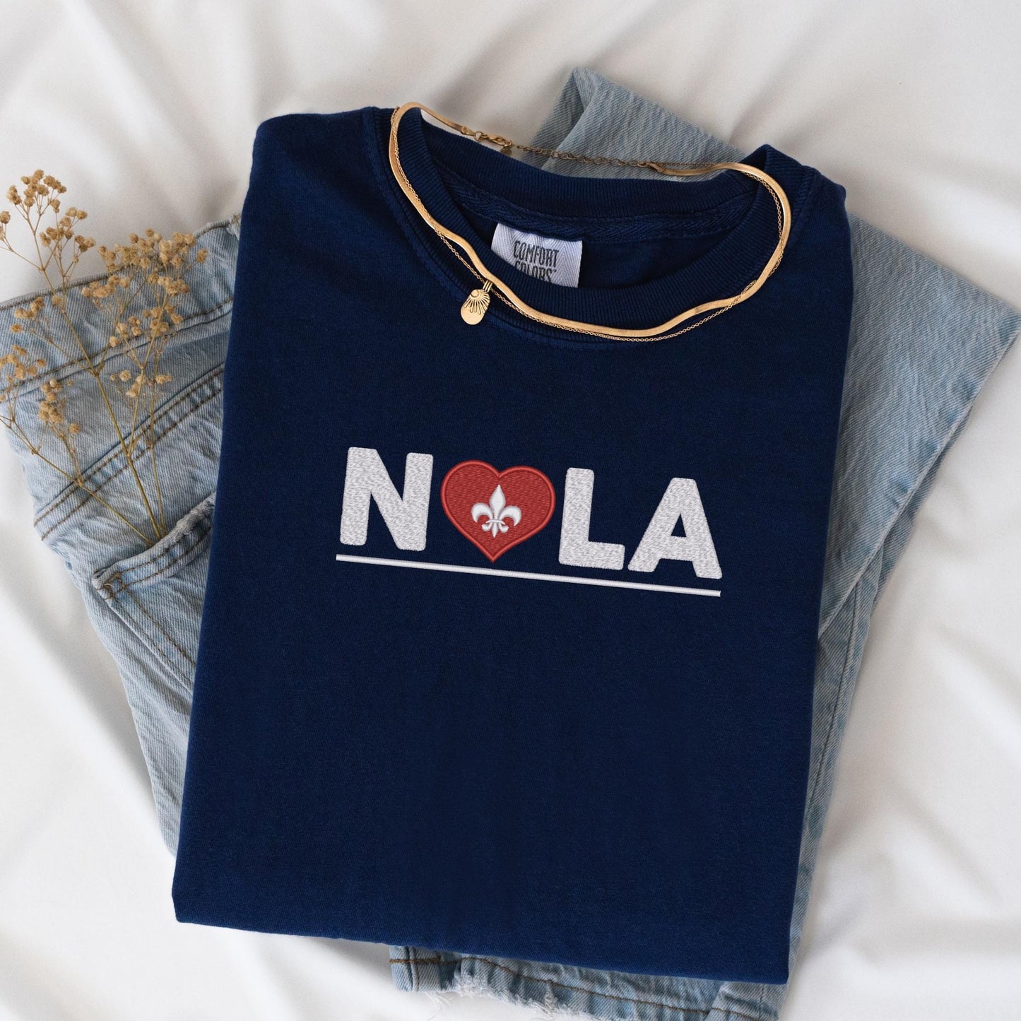 a t - shirt that says nola with a heart and a fleur de