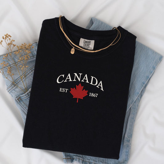 a canada t - shirt sitting on top of a pair of jeans