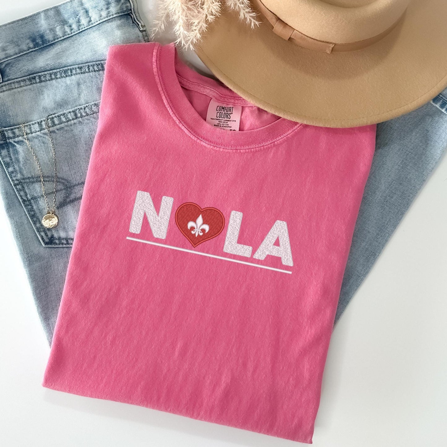 a pink shirt that says nola with a heart on it