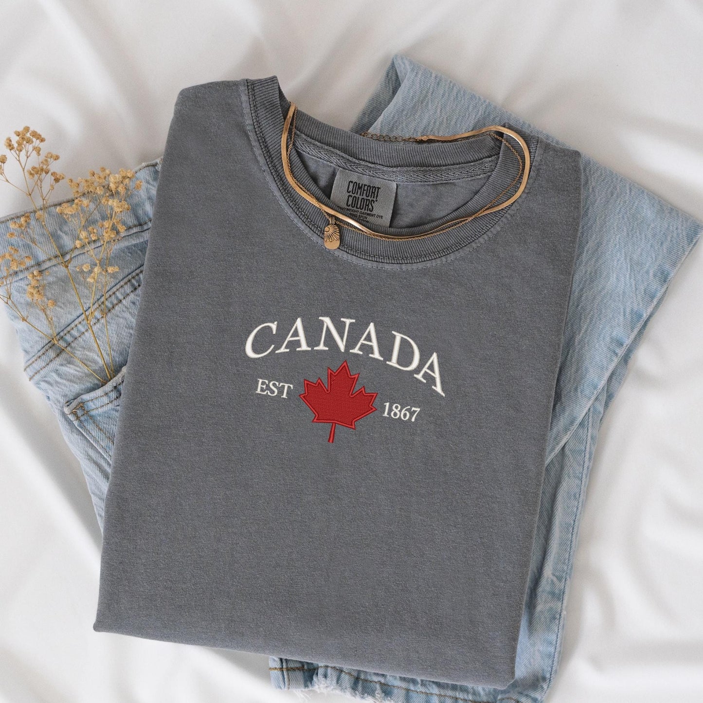 a canada t - shirt sitting on top of a pair of jeans
