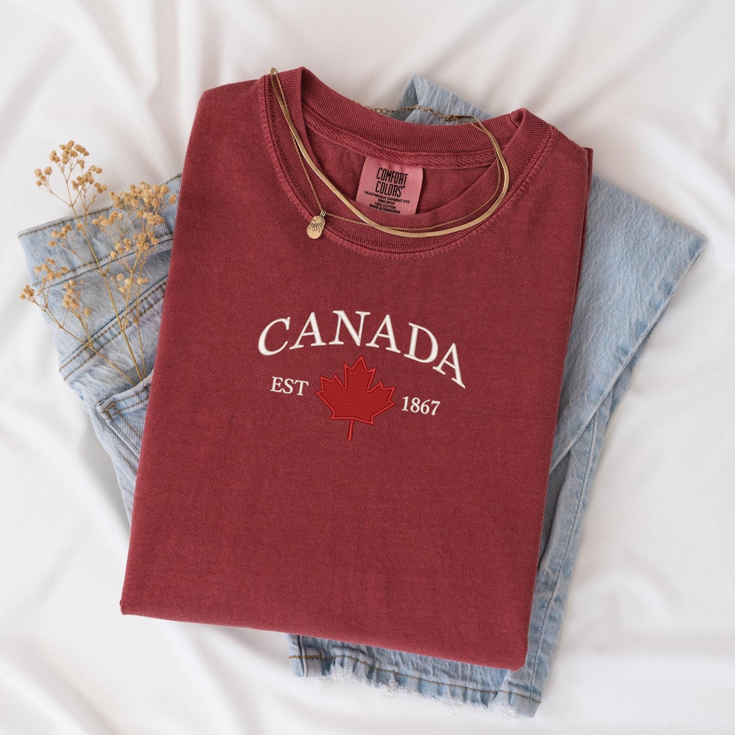 a canada t - shirt is laying on a bed next to a pair of jeans